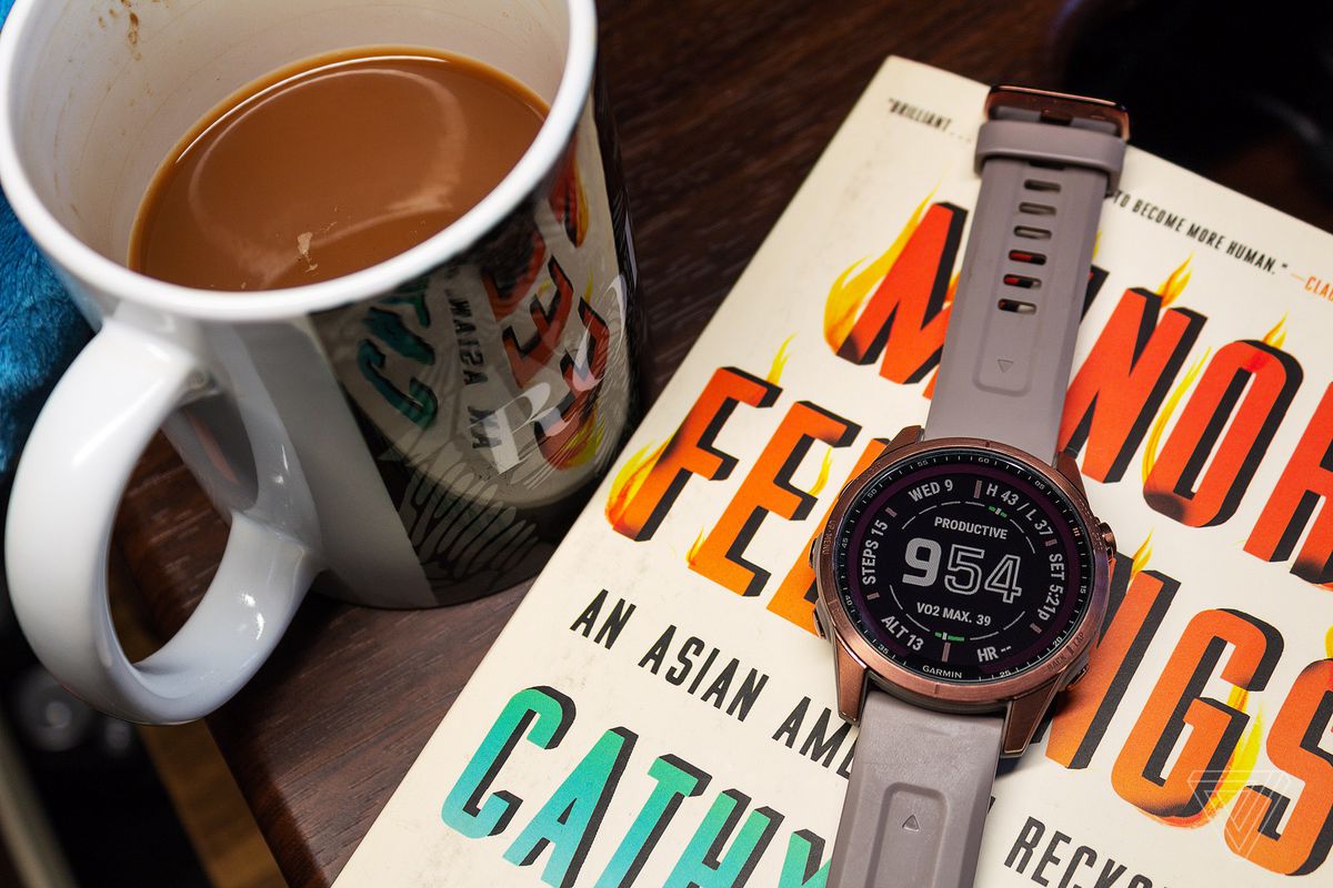 The Garmin Fenix 7S connected  apical  of a publication  and adjacent  to coffee.