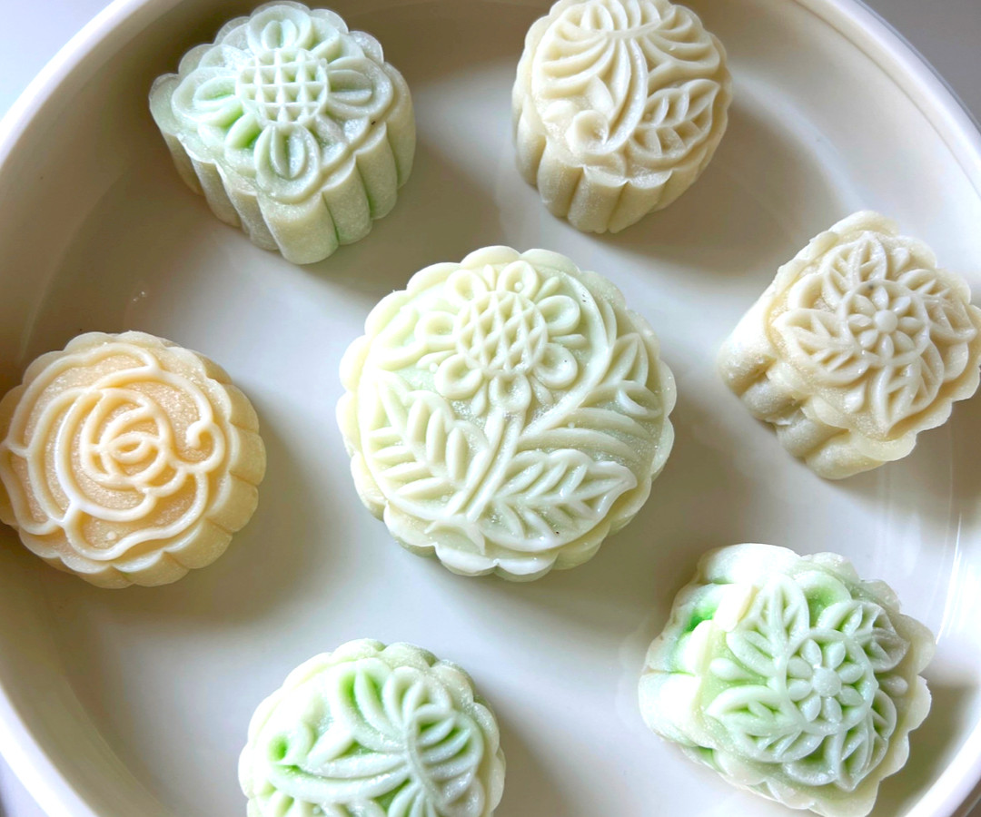 Pale orange and green mooncakes have flower imprints on them.