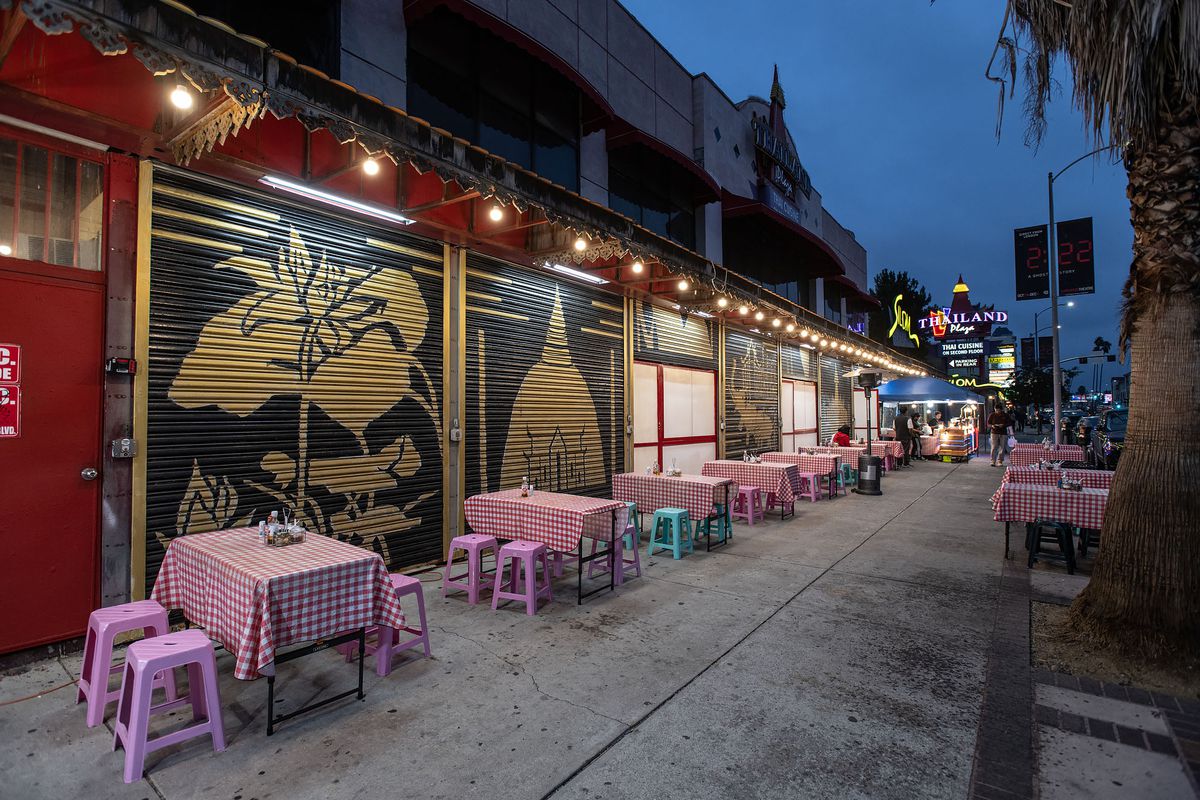 Tables with plastic chairs and an outdoor kitchen at Thai pop-up restaurant Rad Nah Silom in East Hollywood, California.