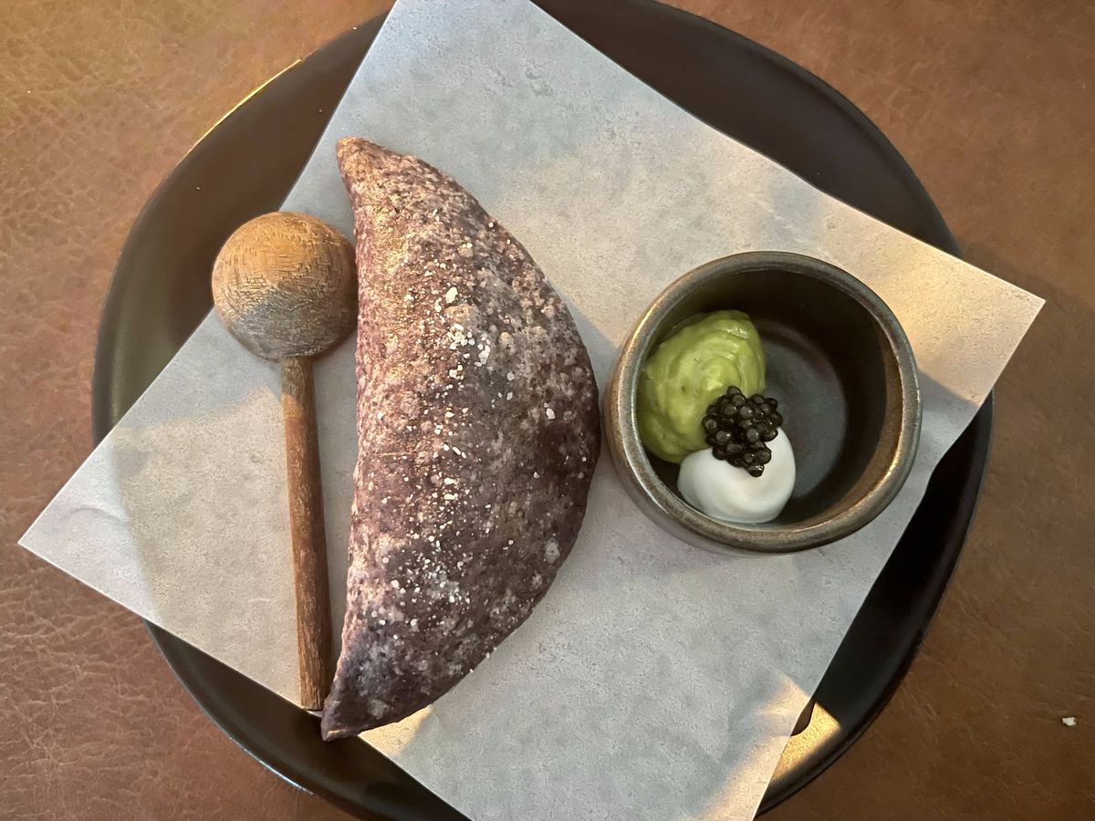 A crimped quesadilla served with a side of guacamole, crema. and caviar.