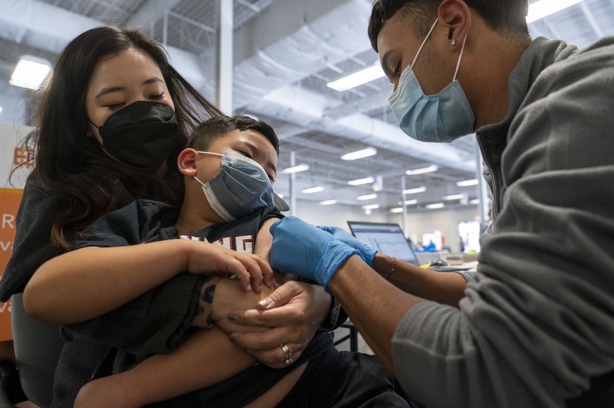 Eun Sem Kil, left, comforts her son Enzo Garcia, 6, center, after he received a dose of the Pfizer COVID-19 vaccine, at an Esperanza Health Centers site at 6057 S. Western in November.
