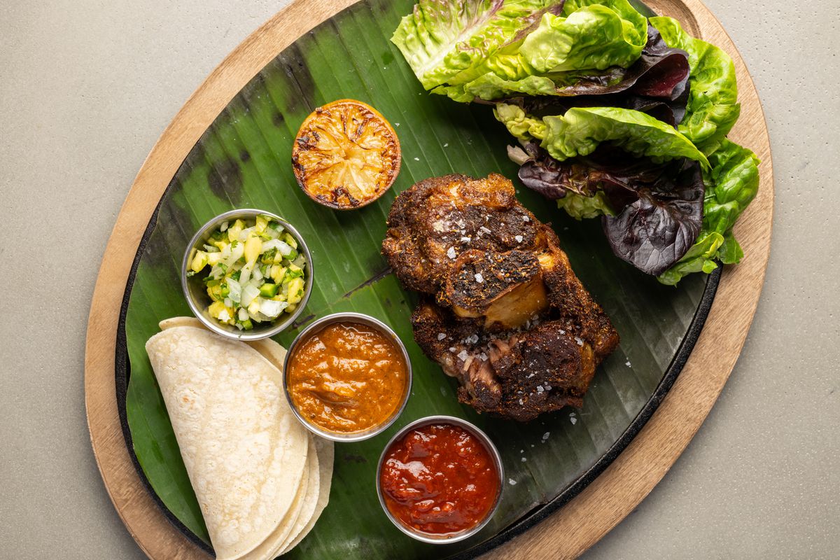 A dish with tortillas, pork, and lettuce on top of a banana leaf at Crawford’s Social in Westlake Village, California.
