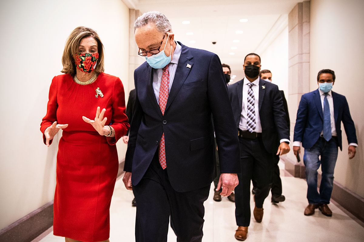 House Speaker Nancy Pelosi and Senate Minority Leader Chuck Schumer walk down a Capitol Hill corridor talking to one another.