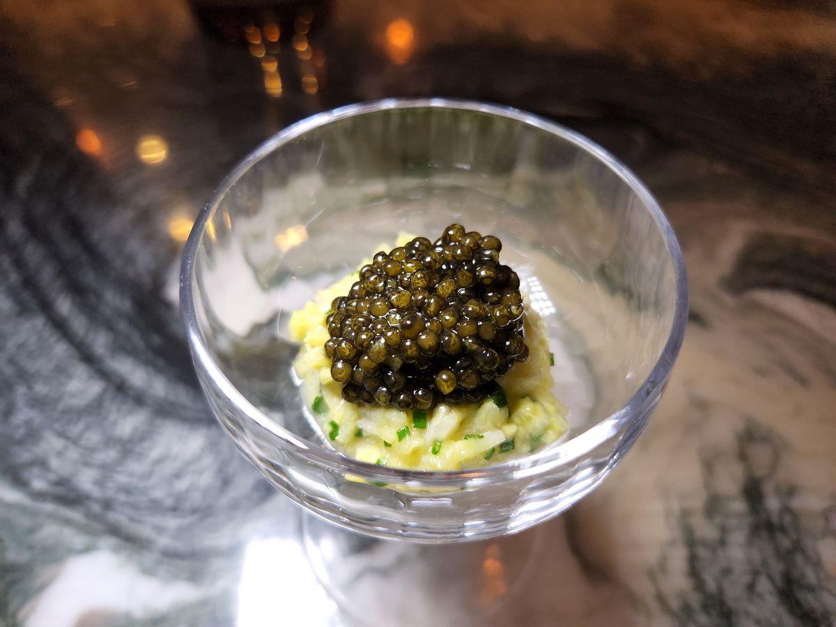 Delicate dish of caviar and corn from a fancy restaurant served in a glass.