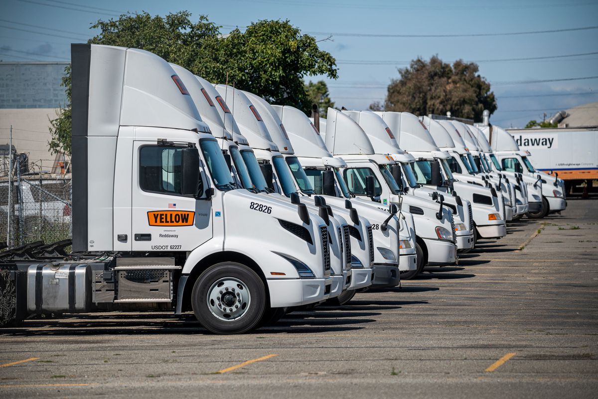 A row of identical semis in a parking lot.