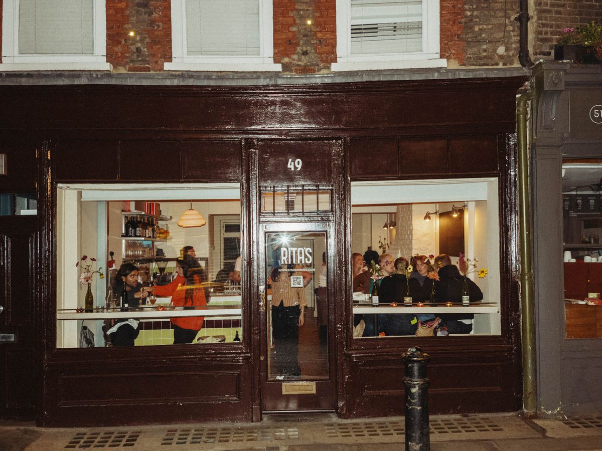 Guests sit at two windows of a small, bistrot-style restaurant, with a black door in the middle.