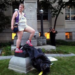 Claire Meddock, 21, stands on a toppled Confederate statue on Monday, Aug. 14, 2017, in Durham, N.C. Activists on Monday evening used a rope to pull down the monument outside a Durham courthouse. The Durham protest was in response to a white nationalist rally held in Charlottesville, Va, over the weekend. Authorities say one woman was killed Saturday after one of the white nationalists drove his car into a group of counterprotesters. (AP Photo/Jonathan Drew)