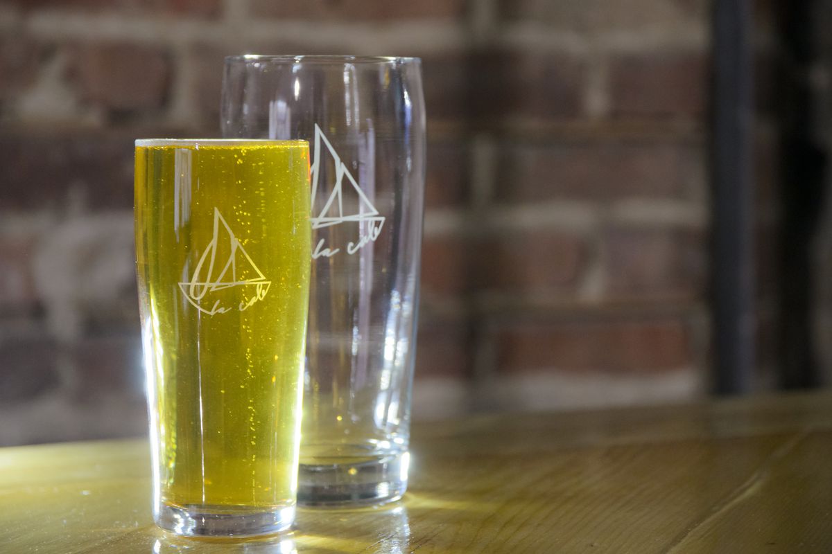 Two glasses with a yacht design on them on a table in front of a brick background.