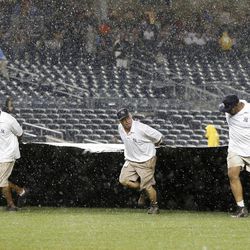 Groundskeepers pull the tarp over the field as rain falls in a baseball game between the New York Yankees and the Boston Red Sox at Yankee Stadium in New York, Sunday, June 2, 2013. 