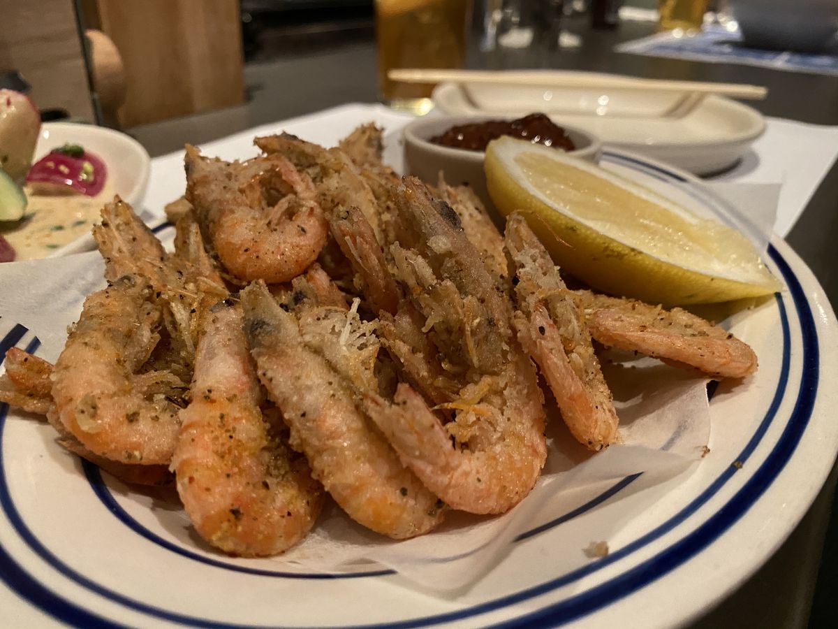 Fried head-on shrimp on a white plate with a blue border