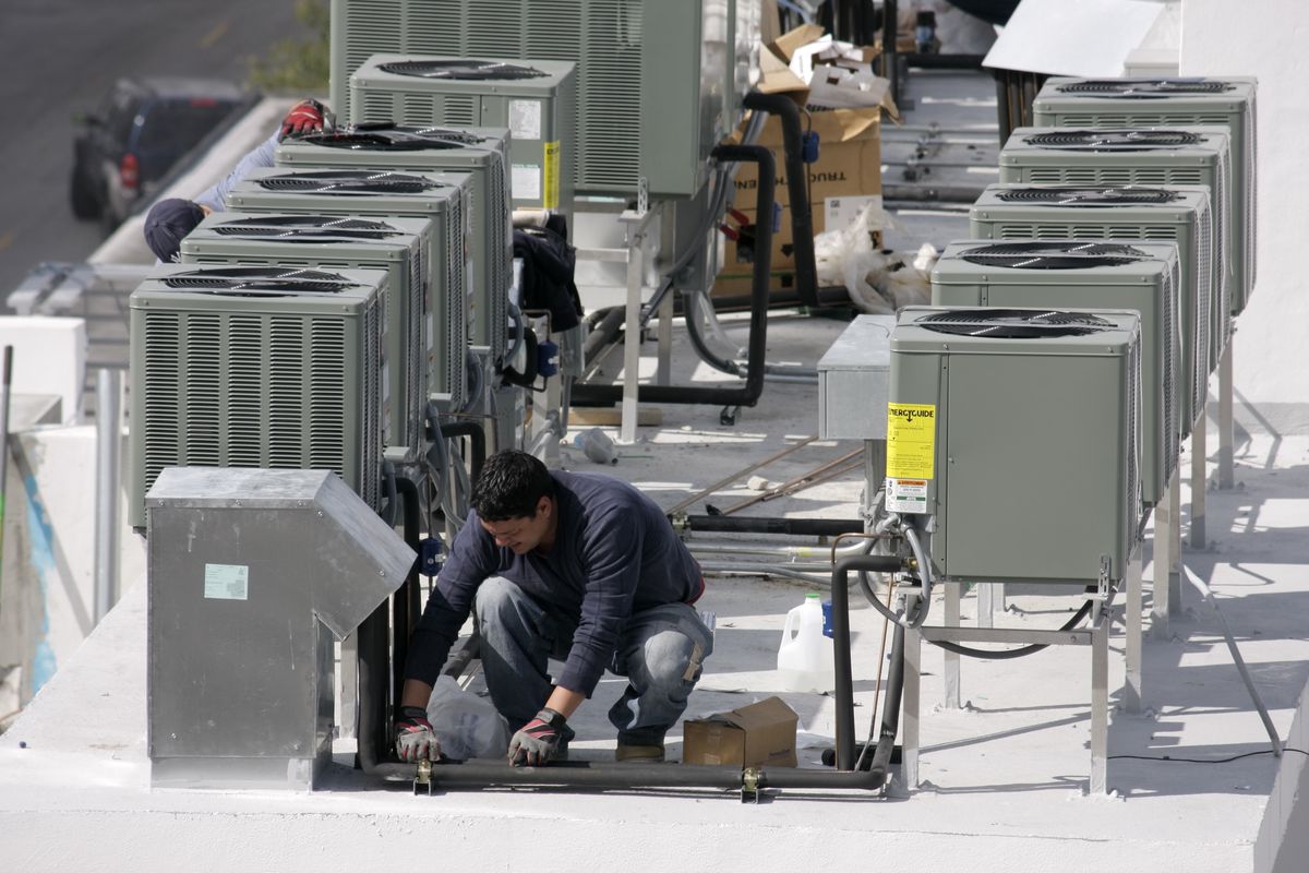 A worker on a rooftop installing air conditioning at a hotel on Ocean Drive