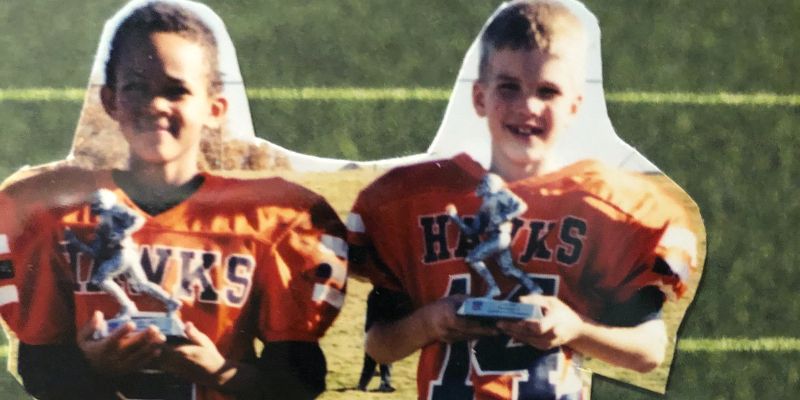 Left to right: Derrick White and Reece Elliot as kids. Both are wearing orange football jerseys that say “Hawks.”
