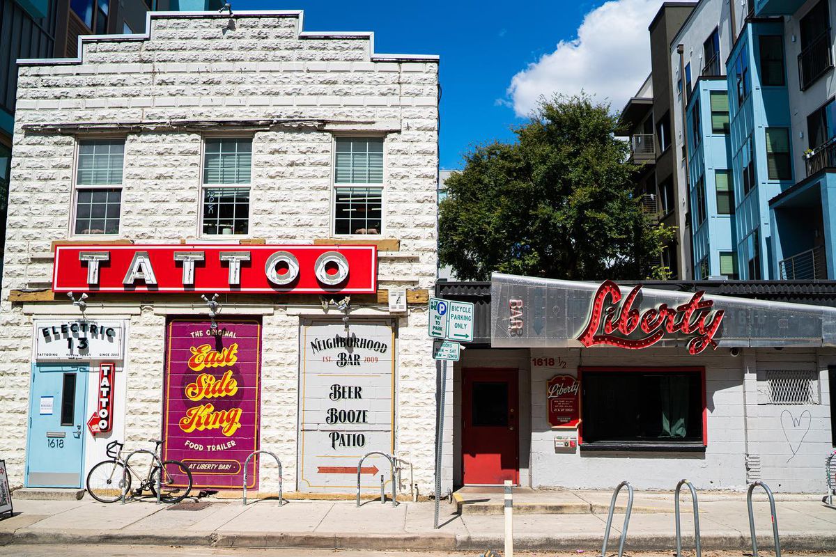 Two building facades, a tattoo shop with a sign that says Tattoo and the other a bar with a sign that says Liberty.
