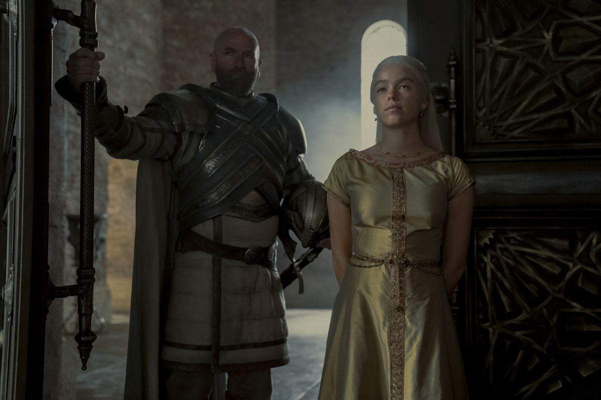 Rhaenyra standing with a guard holding a door to the throne room open for her