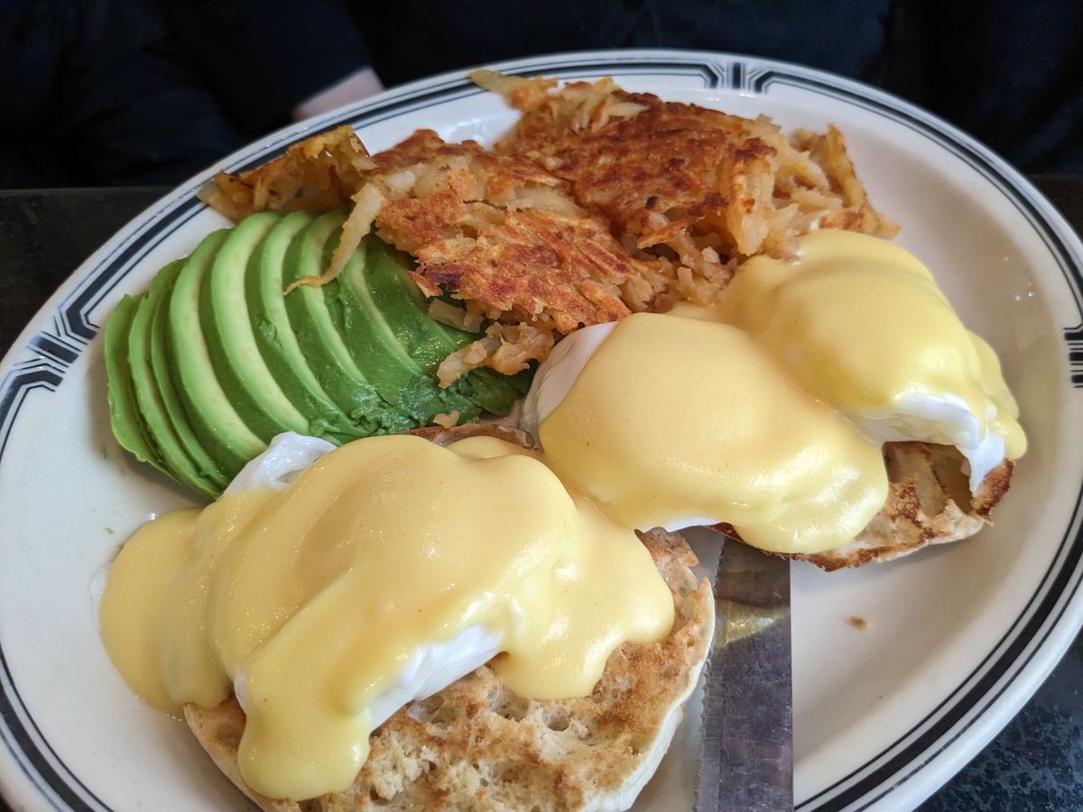 A diner plate with Eggs Benedict, hash browns, and avocado. 