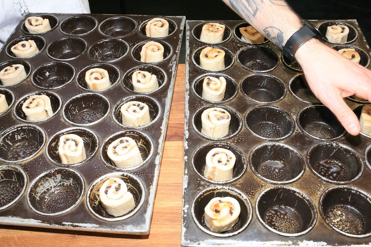 Rolled buns filled with sultanas and brown sugar raw, in tins, ready to bake