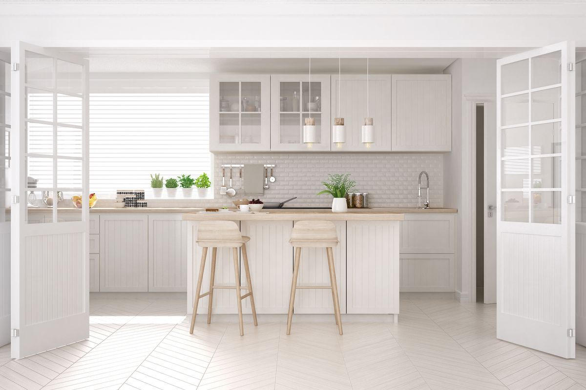a white bright kitchen with window lighting, white cabinets and an island, with appliances 