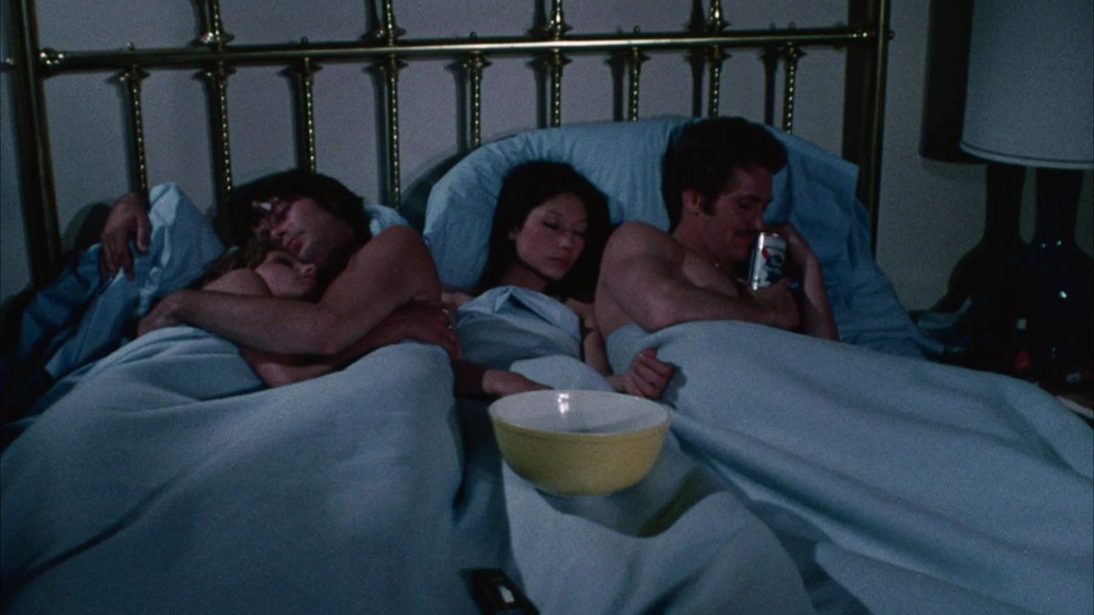 four people sleeping in a bed together in Group Marriage