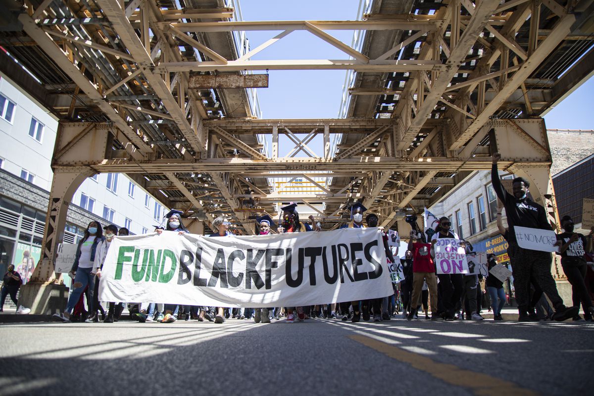 Protesters hold a banner that says “Fund Black Futures” on East 63rd Street in Woodlawn in a June demonstration against police officers in schools.