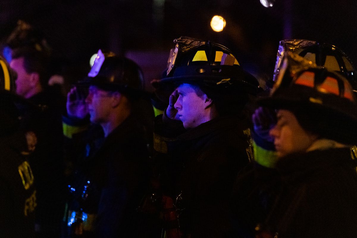 Firefighters salute as the remains of remains of Officer sEduardo Marmolejo and Conrad Gary arrive at the Cook County medical examiner’s office on Tuesday. | Tyler LaRiviere / Sun-Times