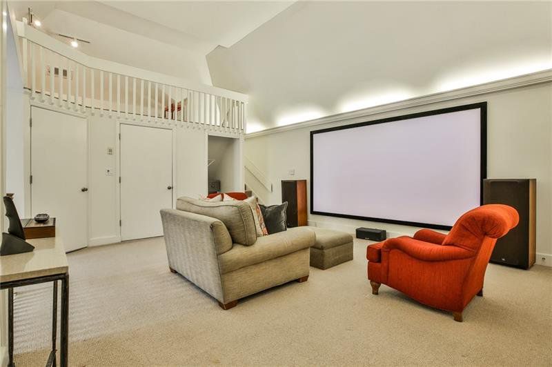 A white media room with red and beige chairs. 