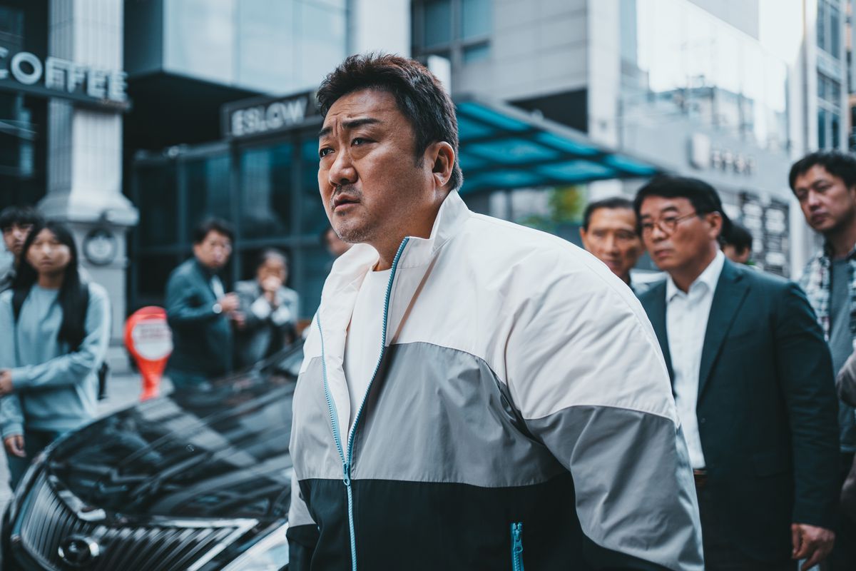 Ma Dong-seok, looking dashing in tracksuits, observes a street brawl in The Roundup: No Way Out.