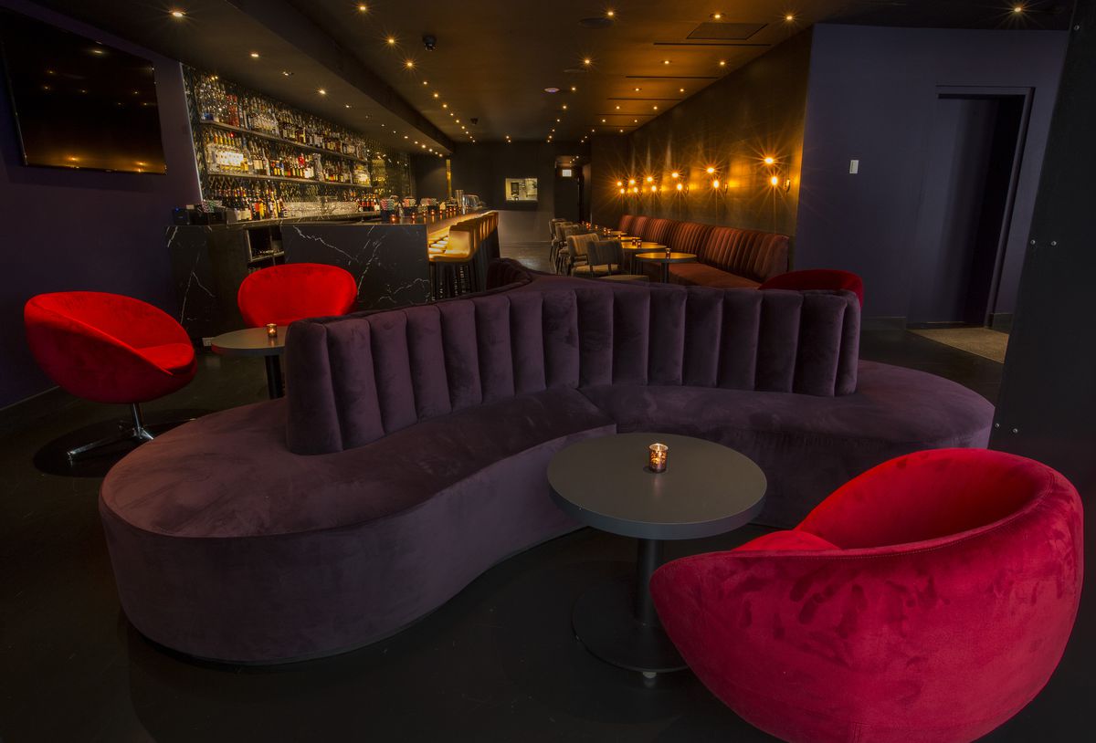 A dark purple circular couch sits next to red round chairs.