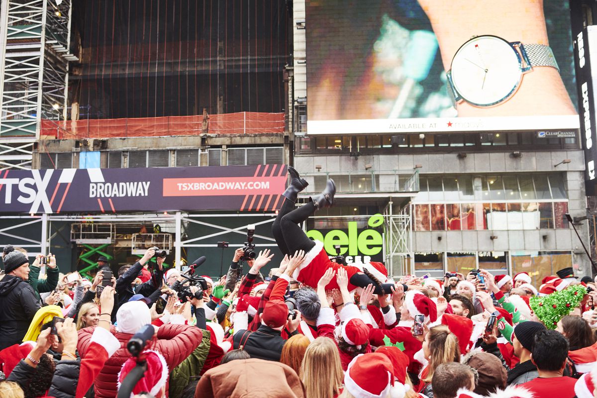 A mob of stumbling New Yorkers dressed in Santa Claus and elf costumes parade through the streets of New York City.