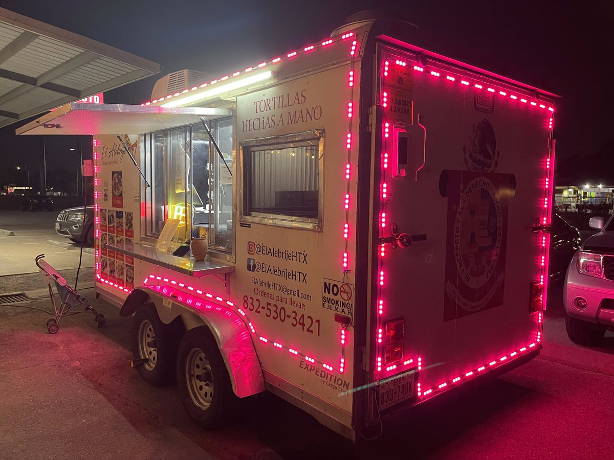 El Alebrije taco truck lit up with pink neon lights.
