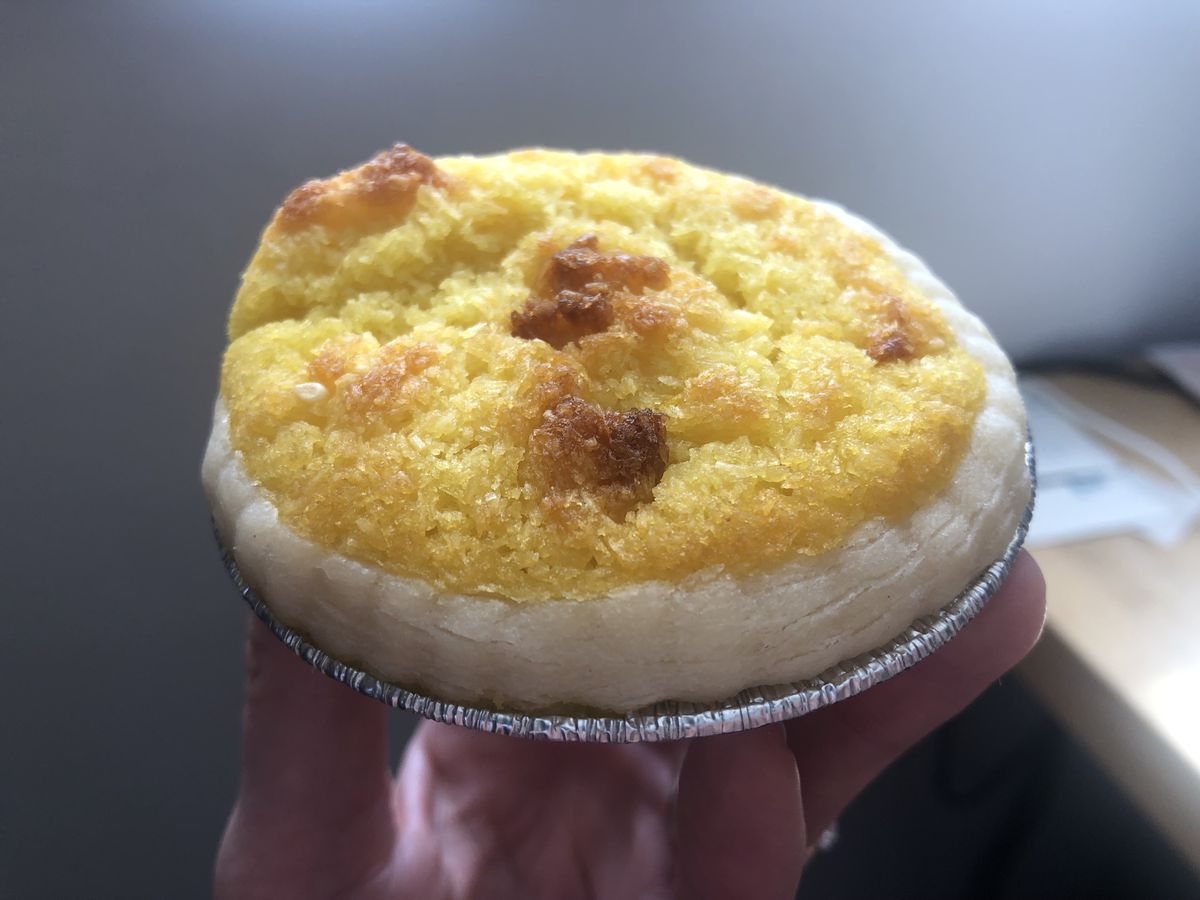 A palm-sized tart with yellow filling in a miniature tin foil holder.