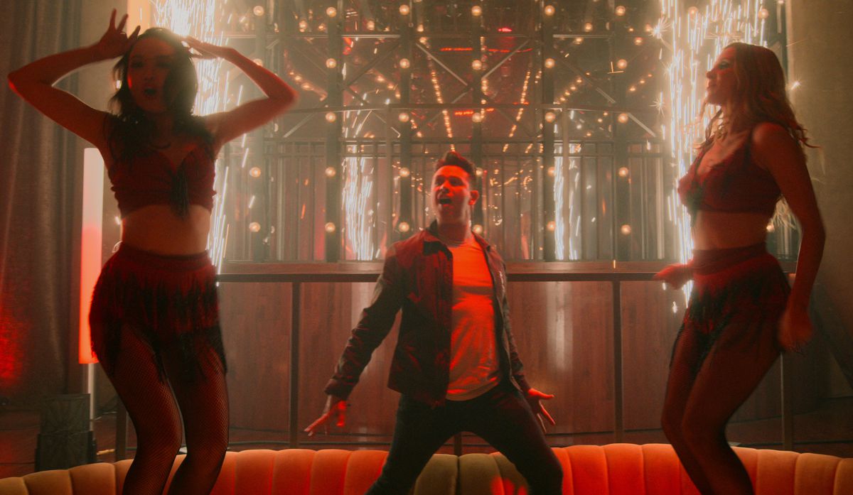 Kevin Alejandro as Dan dances with two women in a “Bloody Celestial Karaoke Jam”