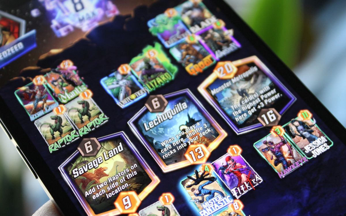 A photo of a game of Marvel Snap, featuring the locations Savage Land, Lechuguilla, and Monster Metropolis, and various cards, on an iPhone.
