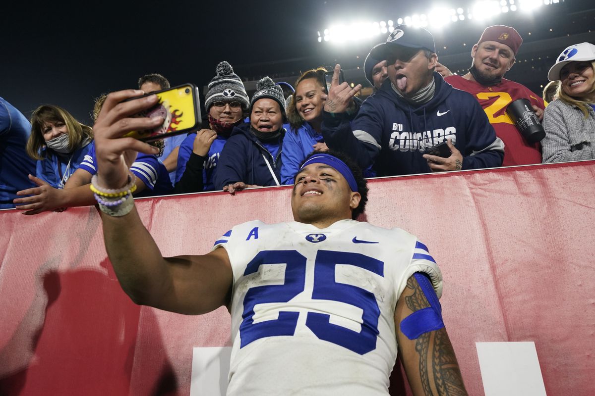 BYU running back Tyler Allgeier (25) takes a selfie with fans after beating Southern California 35-31.