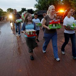 Hannah Slade, center left, Kim Prax, center, and Camber Simmons carry food to those working to help clean. Thousands of volunteers swarm to help residents in Santa Clara work to clean up after flood waters broke the dike Tuesday, Sept. 11, 2012 and destroyed several homes and businesses. 