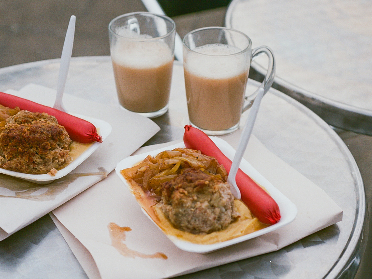 Saveloy, pease pudding, and coffee on a metal outdoor table at Iv’s in Poplar