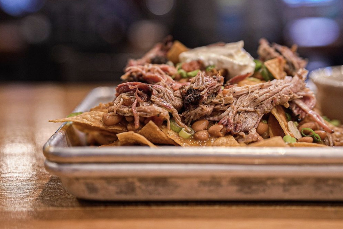A closeup of nachos topped with brisket, scallions, and sour cream