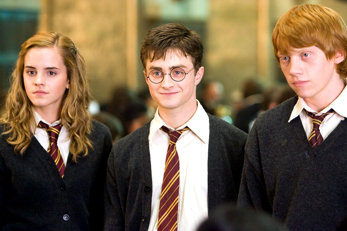 From left to right, Hermione Granger, Harry Potter, and Ron Weasley are wearing their Hogwarts uniforms, and half-smiling towards the camera.