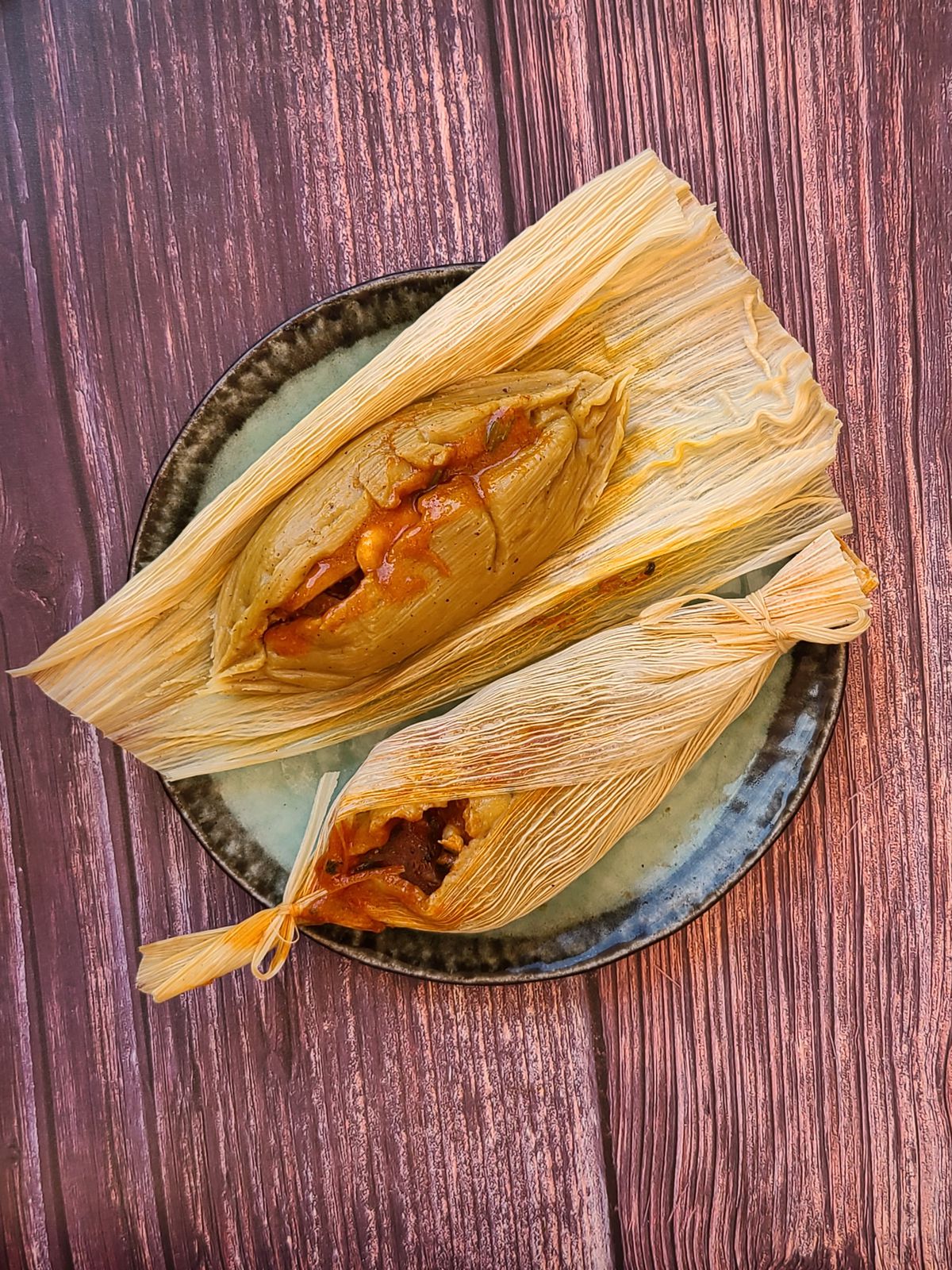 Two tamales de pesco, one partially unwrapped, on a plate.