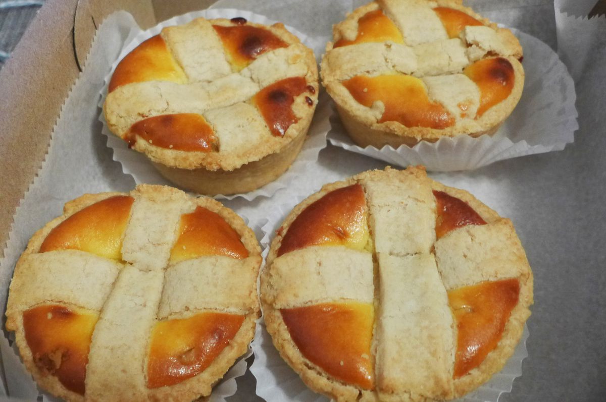 Four round small pies arranged in a square with a pastry cross on top of each one.