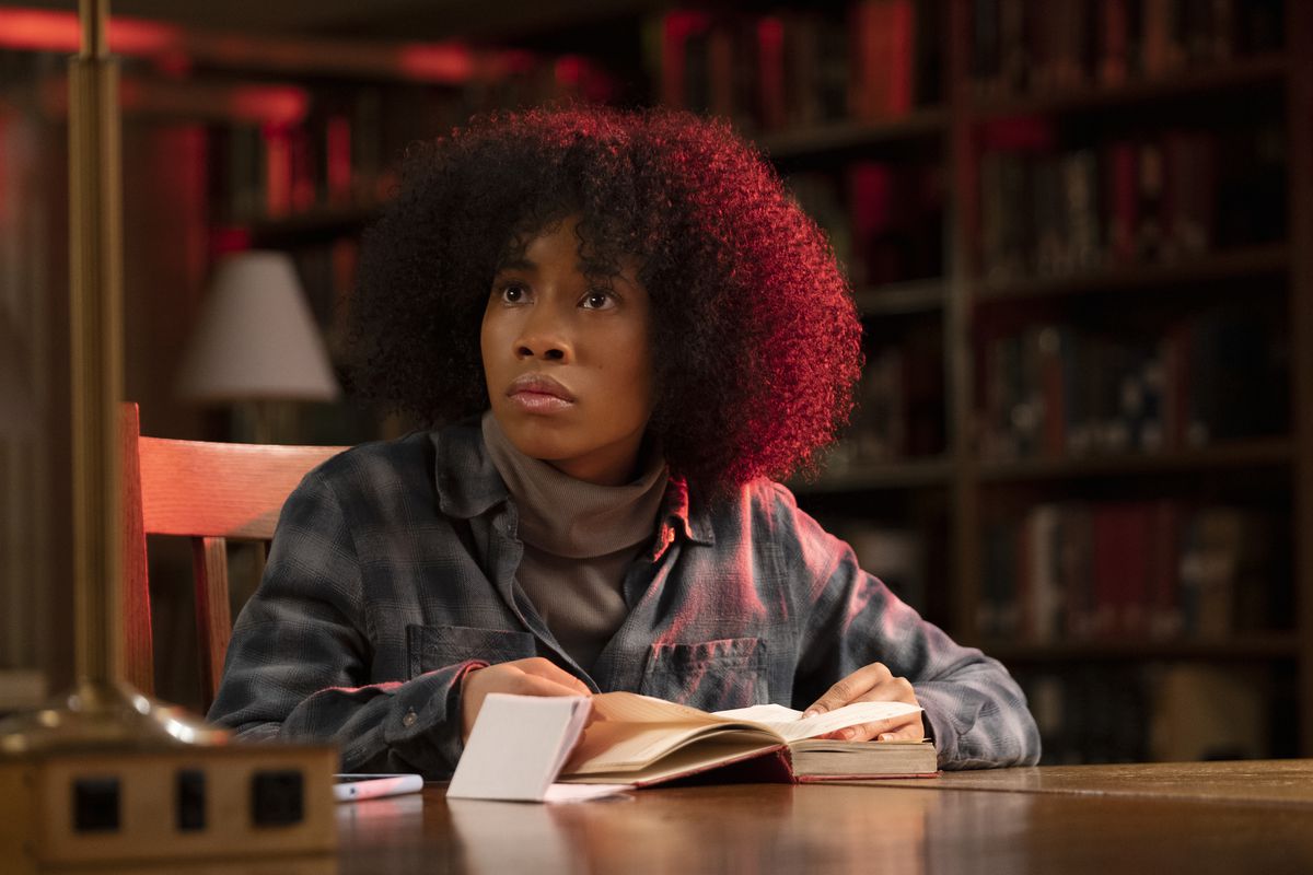 Zoe Renee as Jasmine sits at a table in a student library