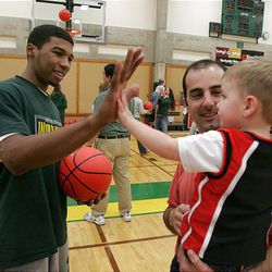 Ronnie Price high-fives Reed Slack, 3, being held by his father, Jason, during Kids Night at UVSC on Feb. 22, 2005.