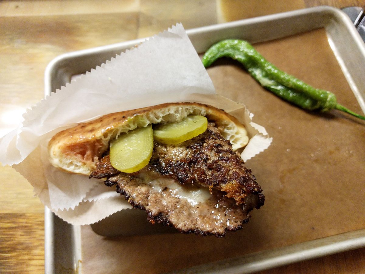 A thick pita with a blackened patty hanging out like a tongue.