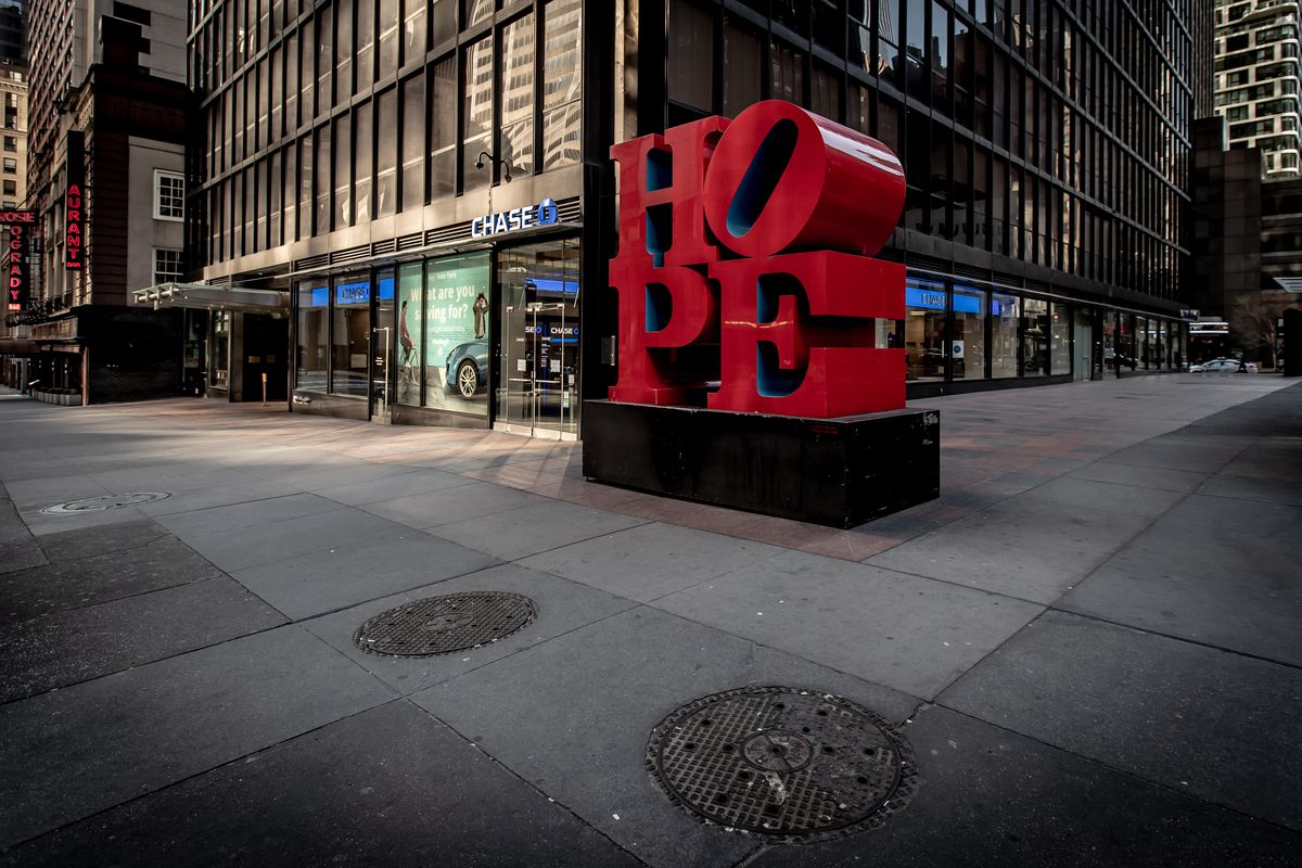 A photo of the Hope sign in red in the financial district. The streets are empty and the base of a building can be seen