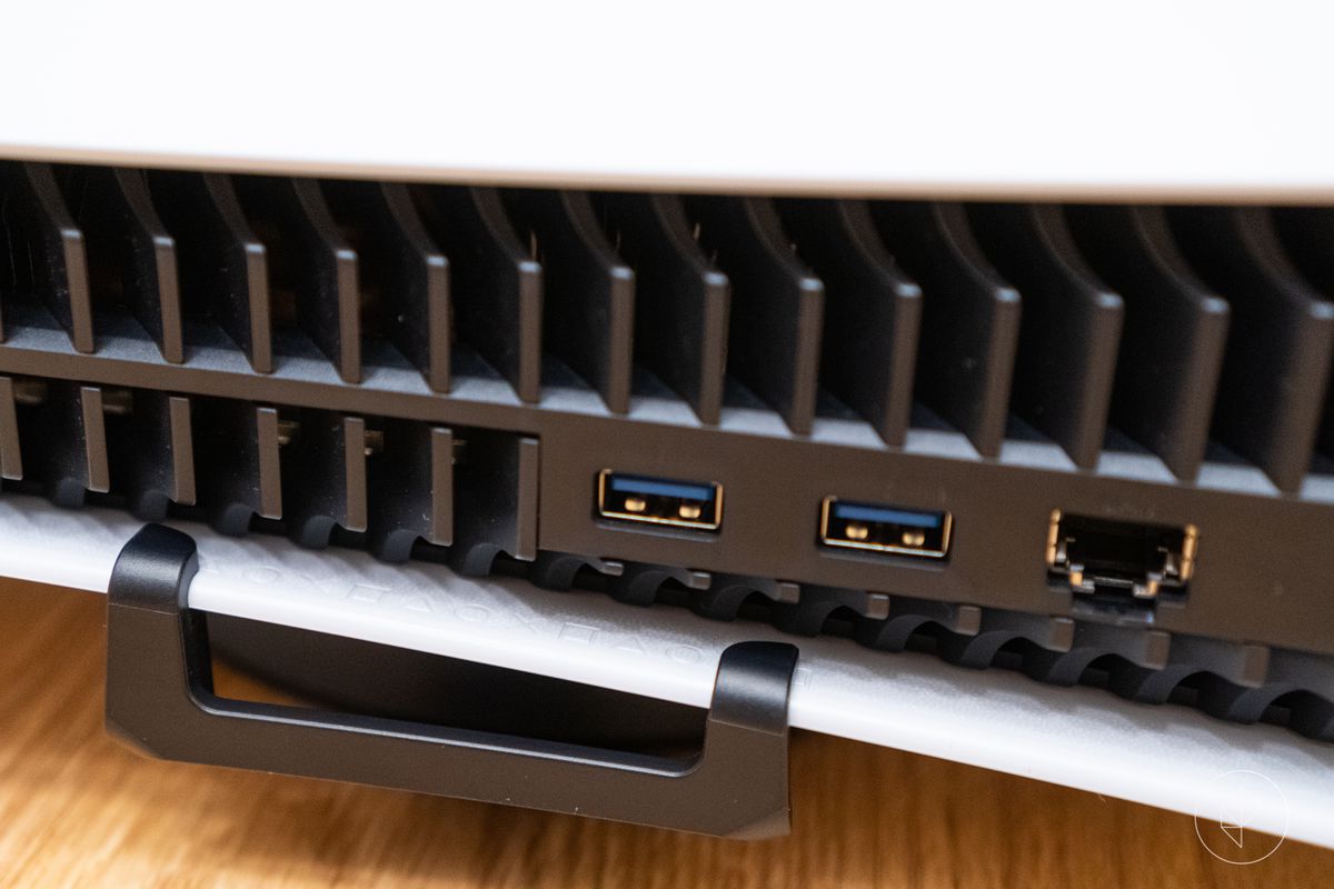 a close-up of the PlayStation 5 stand’s hooks pushed all the way onto the lip of the lower white side panel, to use the console in its horizontal orientation