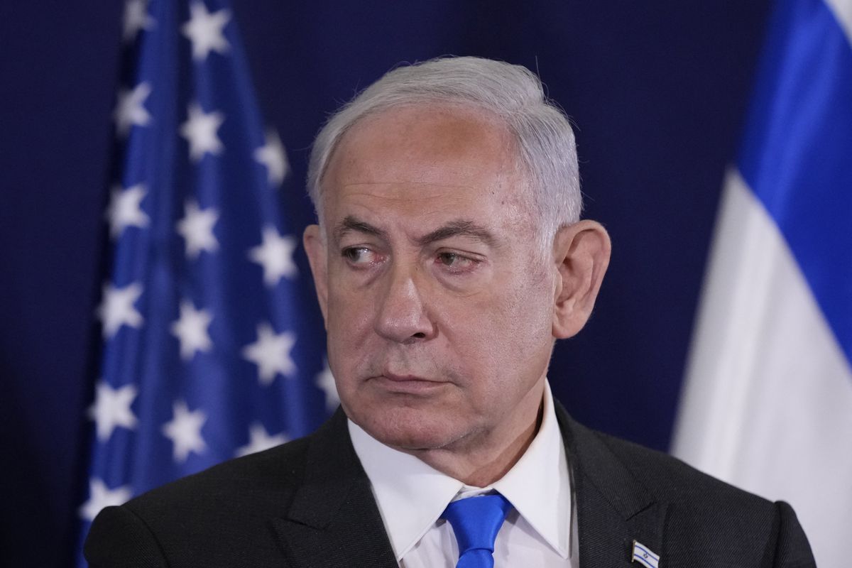 Benjamin Netanyahu’s head and shoulders, with a US flag and an Israeli flag standing behind him.