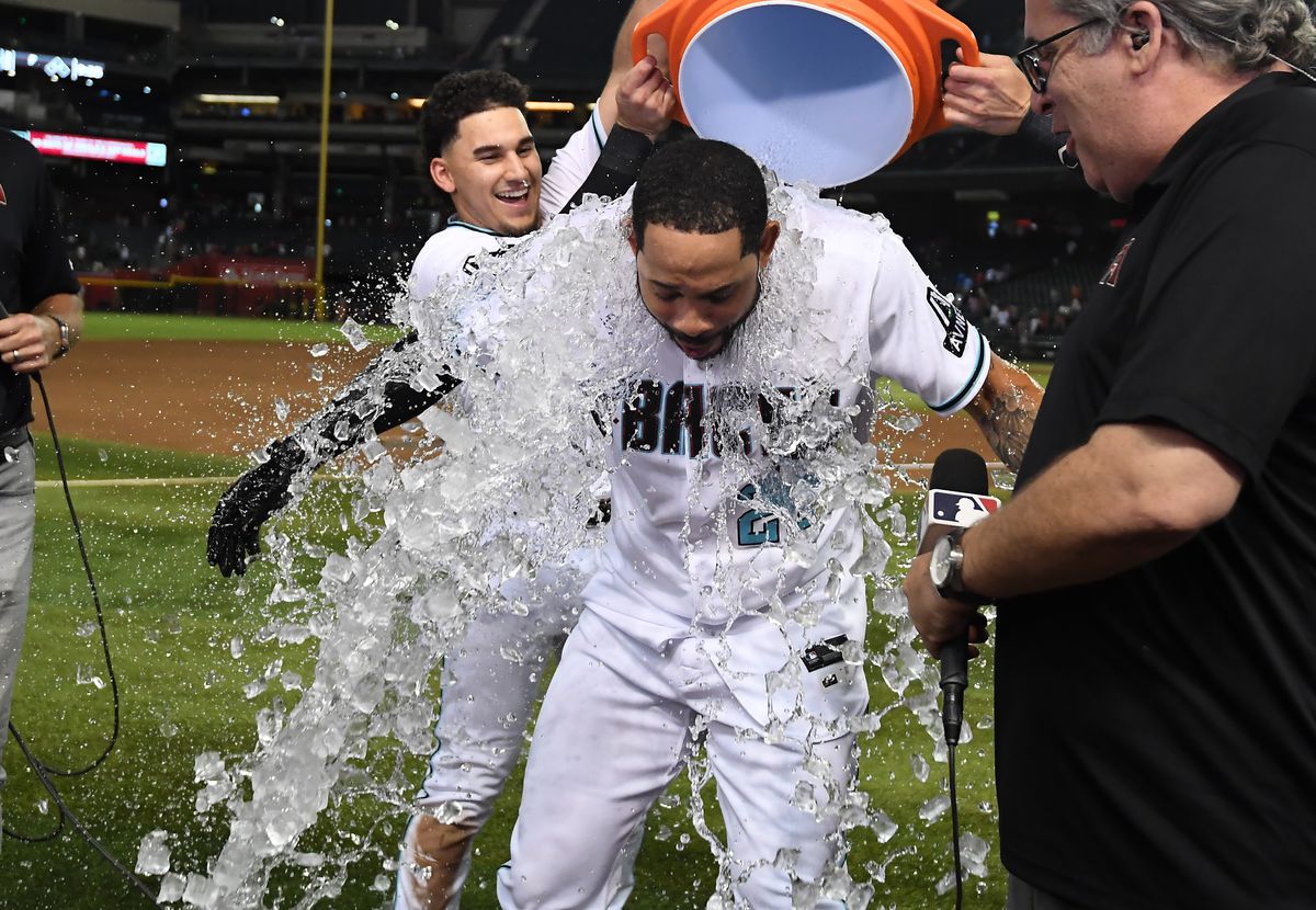 Tommy Pham of the Arizona Diamondbacks has ice water poured over him by teammate Alek Thomas after hitting a two run double to beat the Texas Rangers 4-3 in eleven innings at Chase Field on August 21, 2023 in Phoenix, Arizona.
