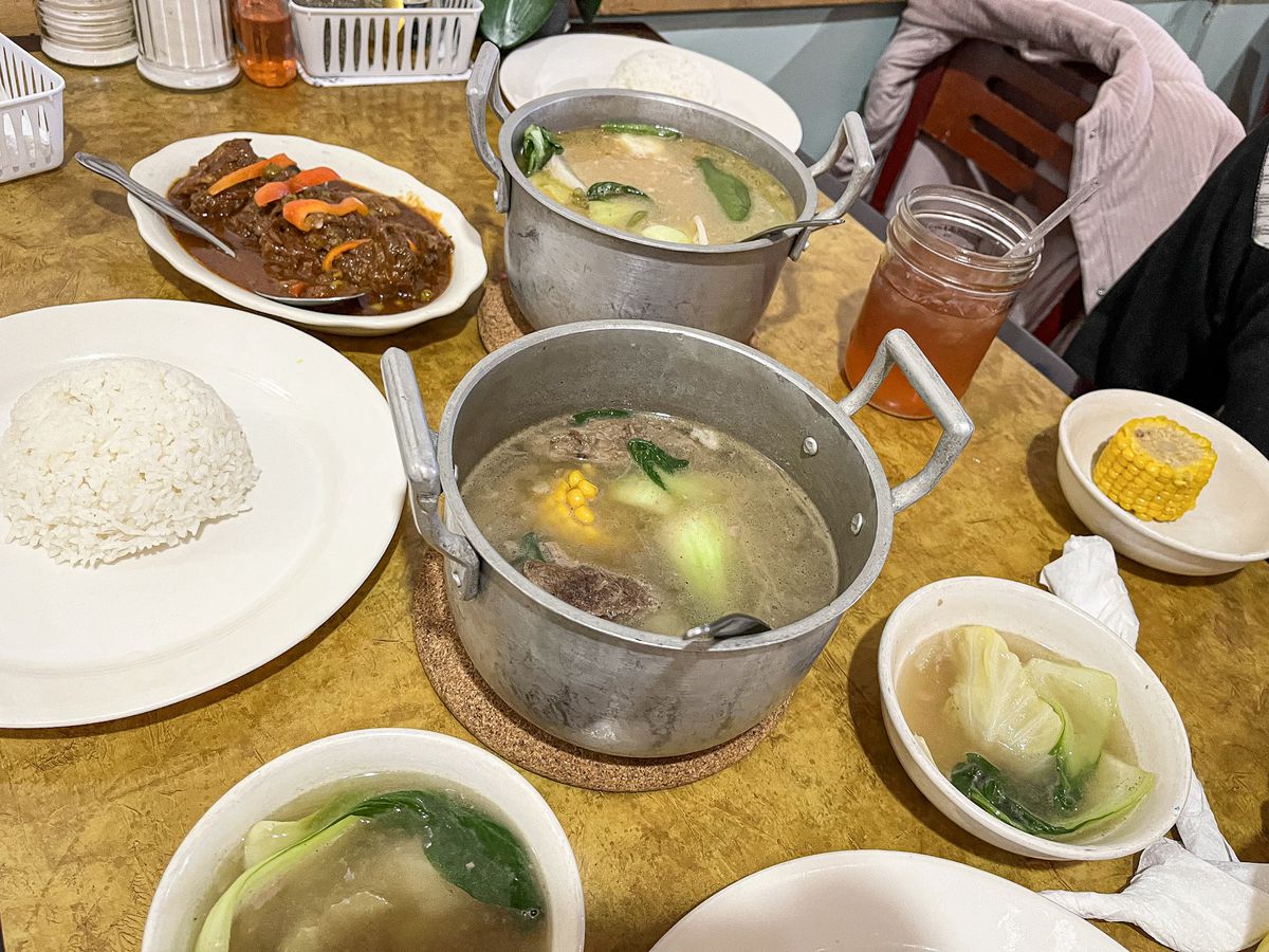 A collection of dishes with a soup in the middle.