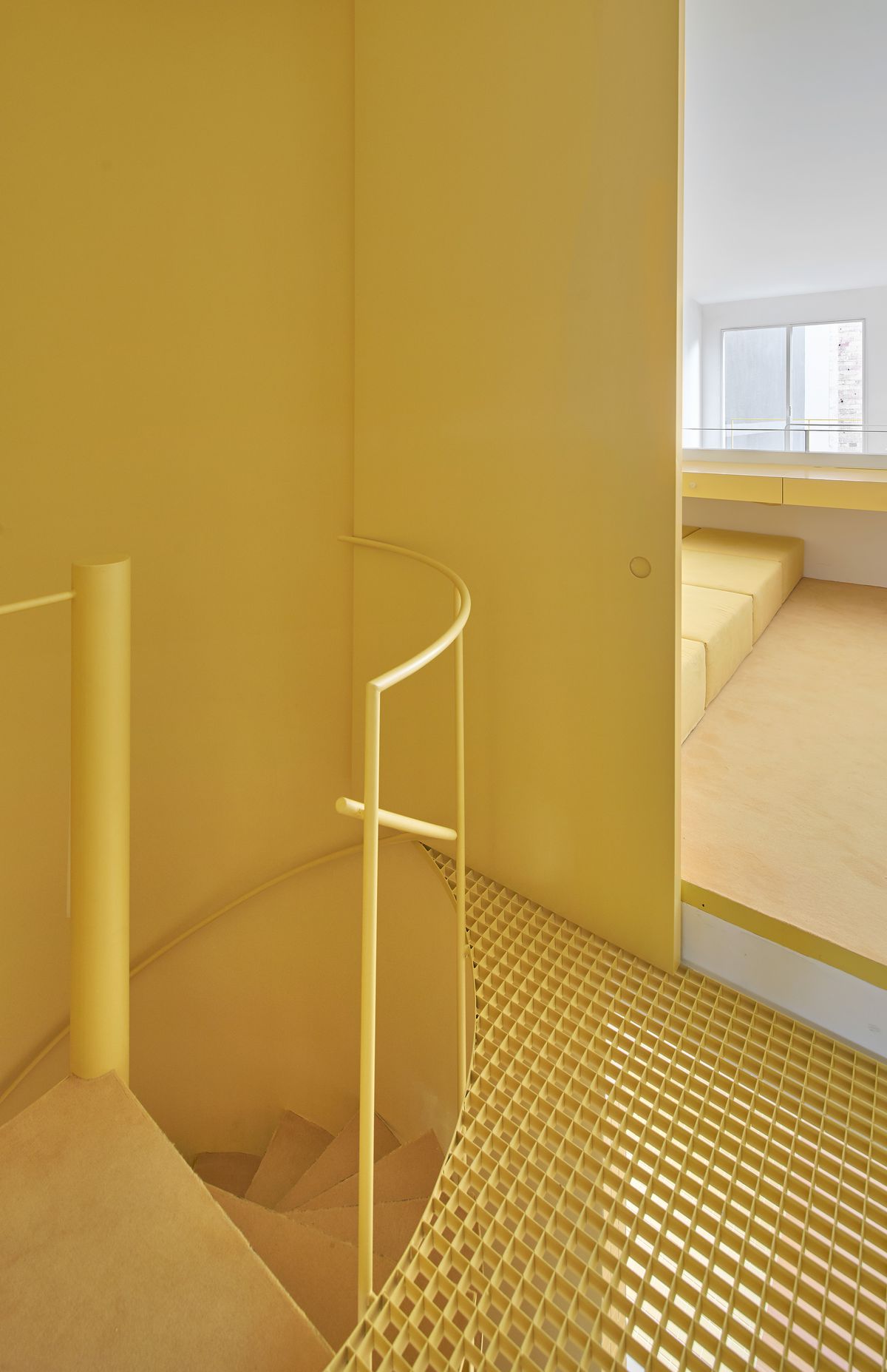Staircase painted in yellow with grates and curved staircase. 