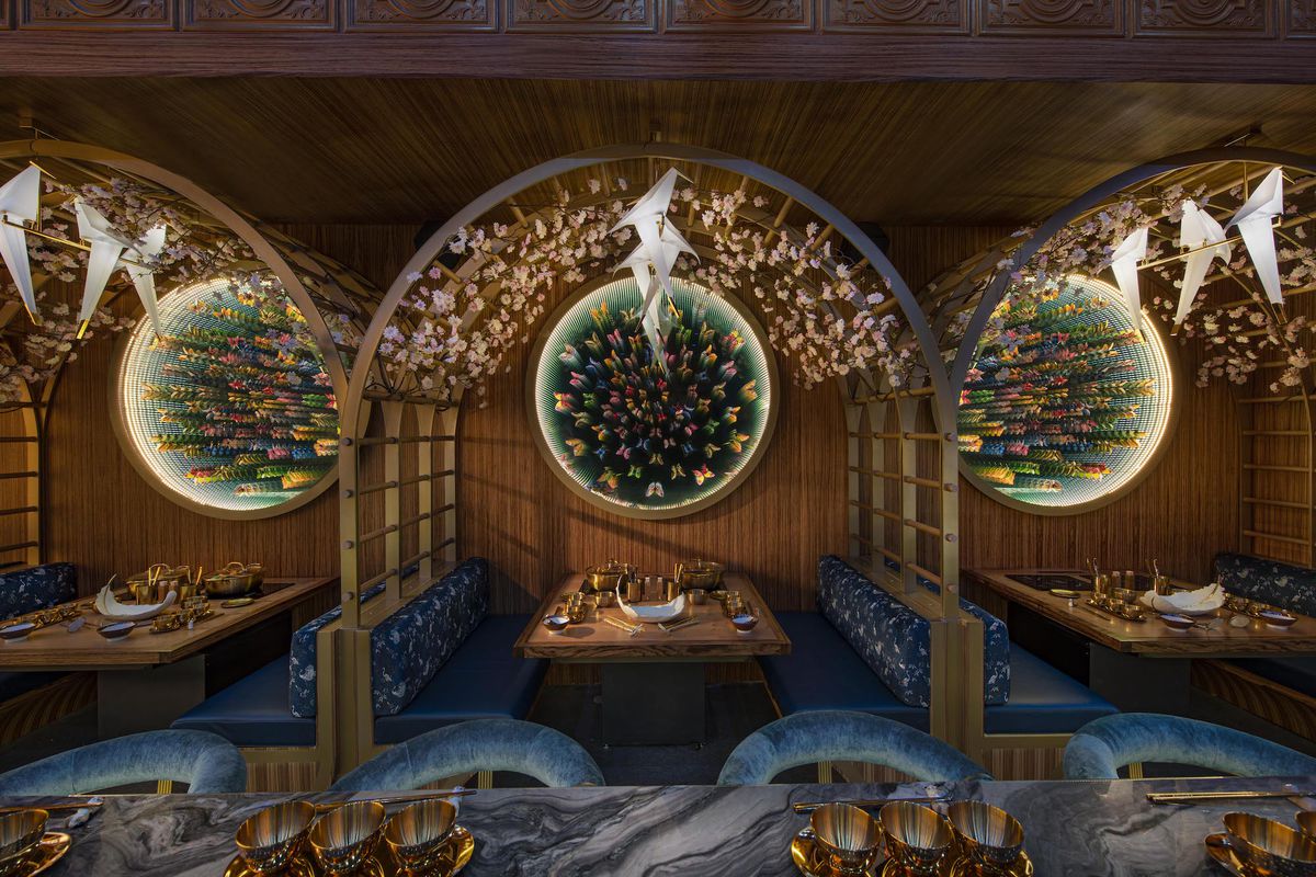 A wide view of dark blue booths with long mirrors and Asian accent pieces like paper cranes at new LA restaurant Lucky Mizu.