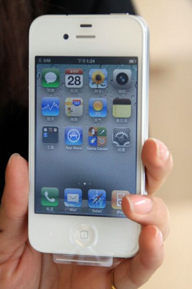 A hand holding an iPhone; half the apps’ names are written in Chinese.